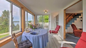 A dining area with a table set for two, large windows, and a staircase leading to an upper level.