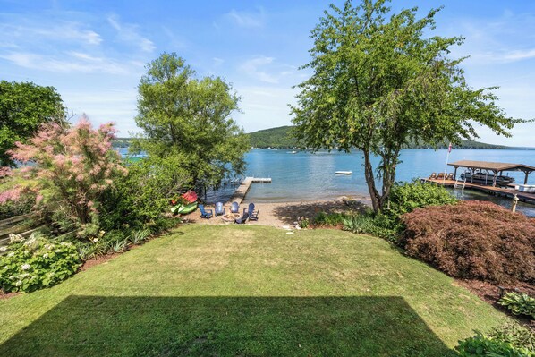 A lakeside property with a grassy lawn, a dock, and a covered seating area.