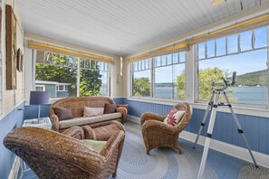 Une pièce meublée de mobilier en osier, avec un télescope et une vue sur un lac.