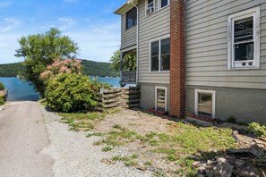 A house with a gravel driveway, a wooden fence, and a view of a lake.