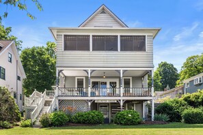 A two-story house with a balcony, a front porch, and a small garden area.