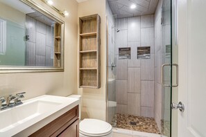 A modern bathroom with a glass-enclosed shower, a large mirror, and a wooden vanity. - Theater Room + Fire Pit: Anchorage Family Retreat (Anchorage)