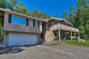 A two-story house with a covered porch, a garage, and a well-maintained lawn. - Theater Room + Fire Pit: Anchorage Family Retreat (Anchorage)