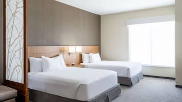A hotel room with two beds, a large window, and a wooden headboard.