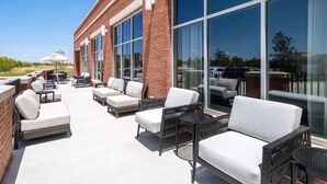 Un patio al aire libre con mobiliario de mimbre y amplias ventanas.