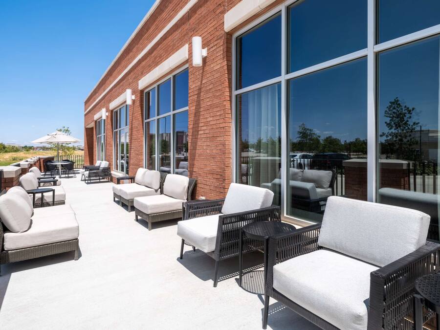 Un espace extérieur aménagé en terrasse, avec des meubles en osier et de grandes fenêtres.