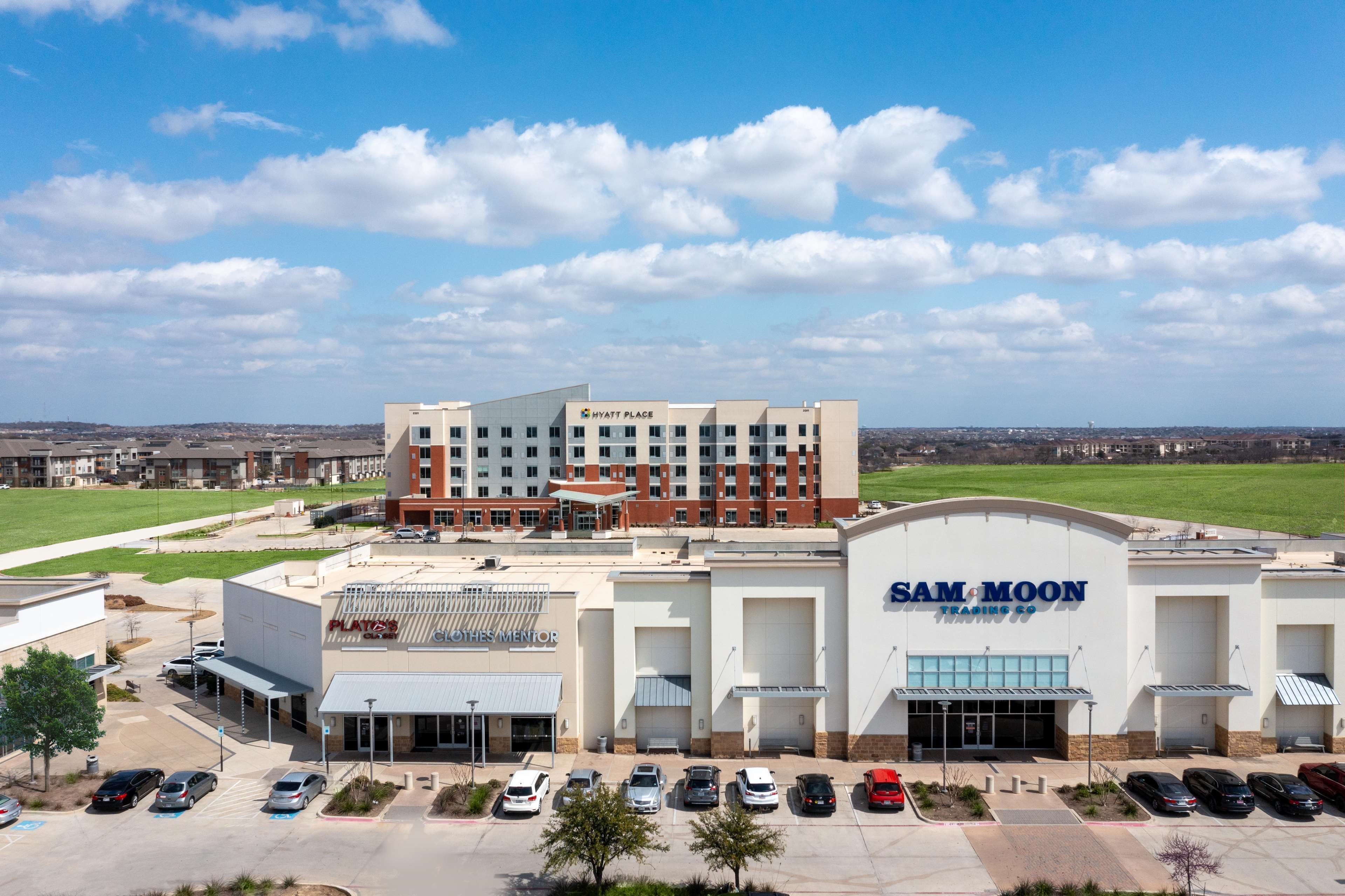 A hotel with a large parking lot and a Sam Moon Trading Co. store.