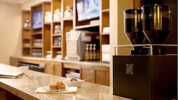 A kitchen counter with a coffee machine, a bowl of cereal, and a cup of coffee.