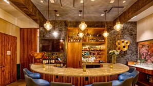Un espace bar doté d’un comptoir circulaire, de plusieurs tabourets et d’un présentoir à bouteilles de vin.