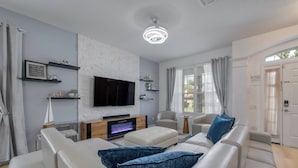 Una sala de estar moderna con una televisión de pantalla plana, una chimenea y un sofá con cojines azules.