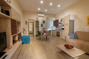 A modern living room with a TV, wooden furniture, a dining area, and a kitchen.