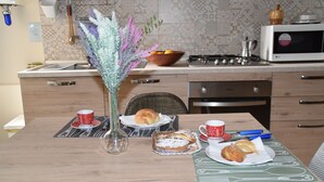 A kitchen with a dining table set for breakfast, including pastries and cups.