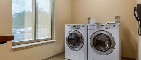 A laundry room with two front-loading washing machines, a window, and a telephone.