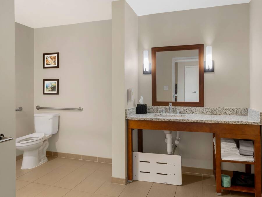 Une salle de bain avec des toilettes, un lavabo avec un miroir et deux tableaux encadrés au mur.