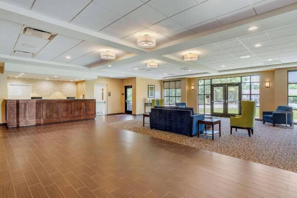 A spacious lobby with a reception desk, seating area, and large windows.