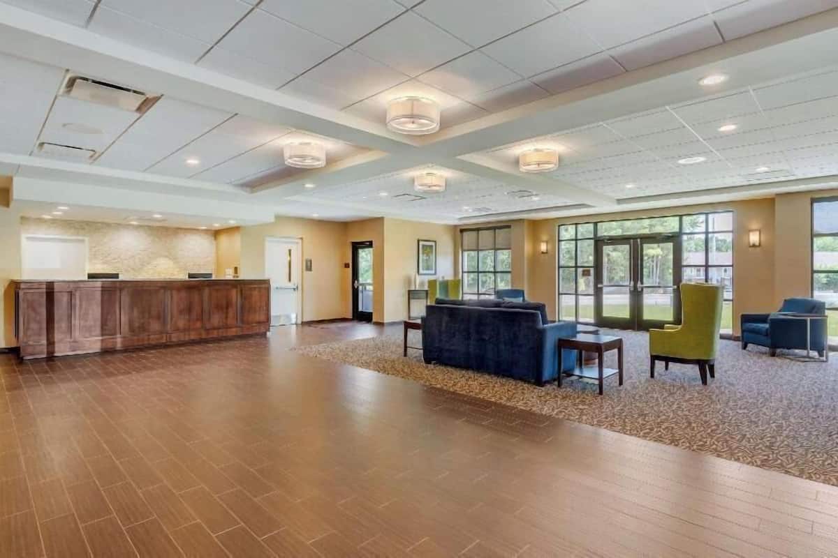 A spacious lobby with a reception desk, seating area, and large windows.