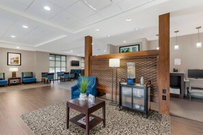 A hotel lobby with a reception desk, seating area, and a television screen.