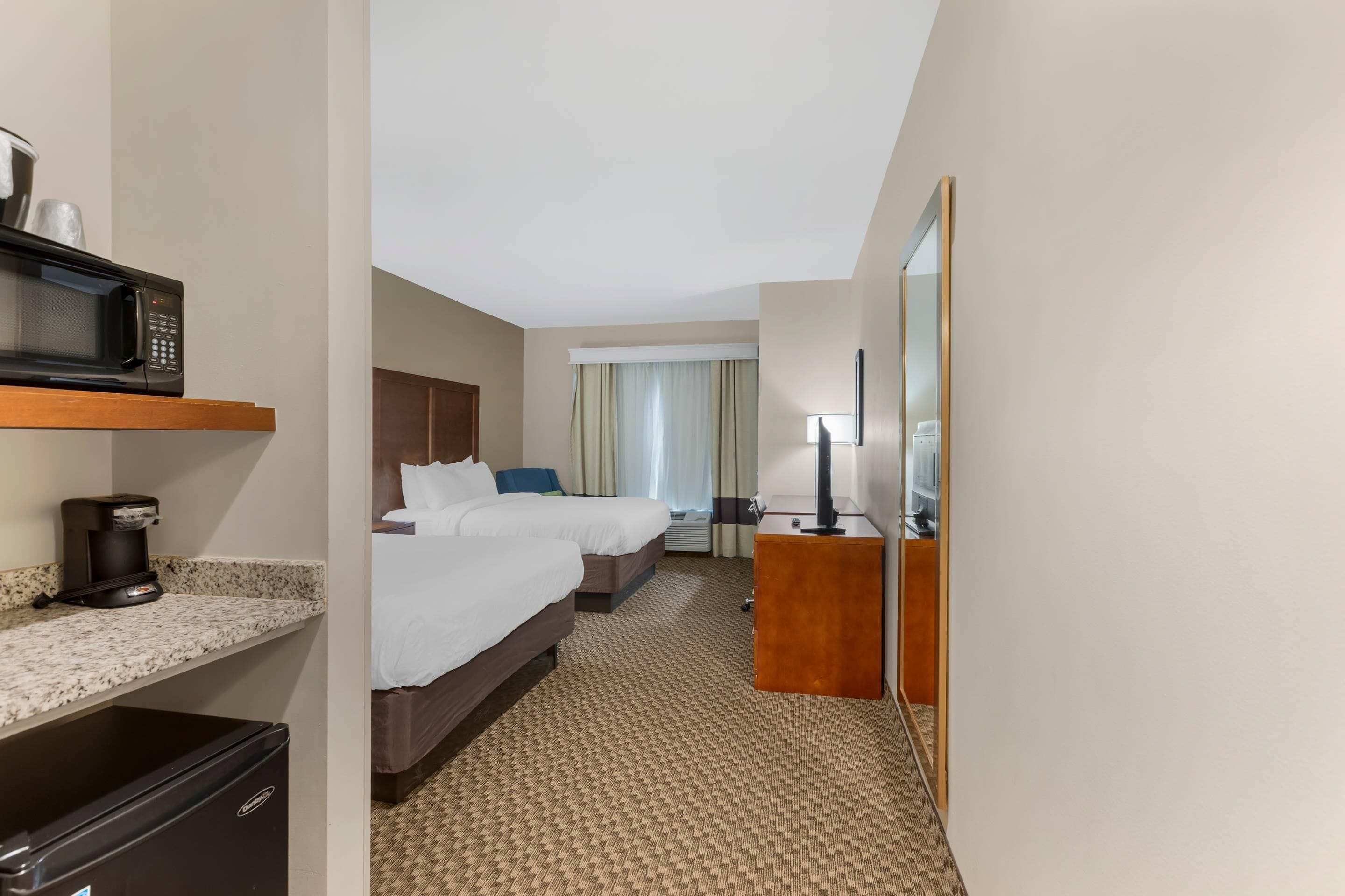 Habitación de hotel con cama, escritorio, microondas, cafetera y armario.