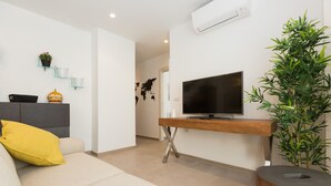 Un salon moderne avec un canapé, un téléviseur posé sur un meuble en bois, une plante et une carte du monde accrochée au mur.
