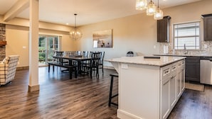 A spacious kitchen with a large island, dark wood flooring, and pendant lighting.
