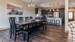 A spacious dining area with a wooden table and chairs, a bench, and a pendant light.