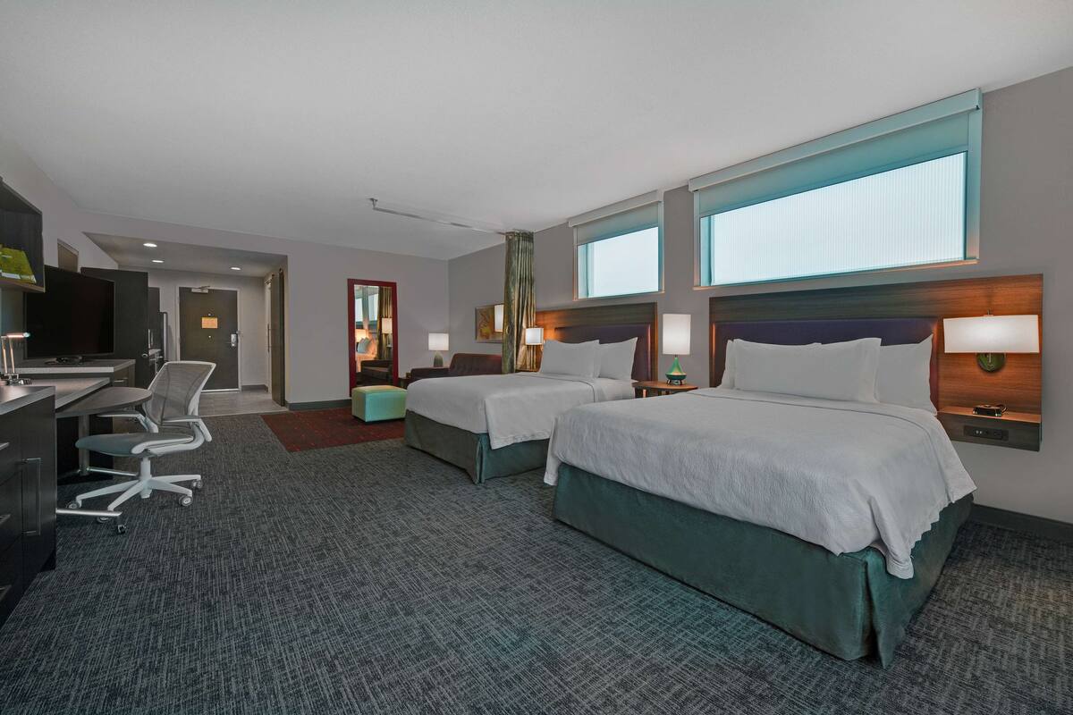 Ein Hotelzimmer mit zwei Betten, einem Schreibtisch und einem Stuhl.