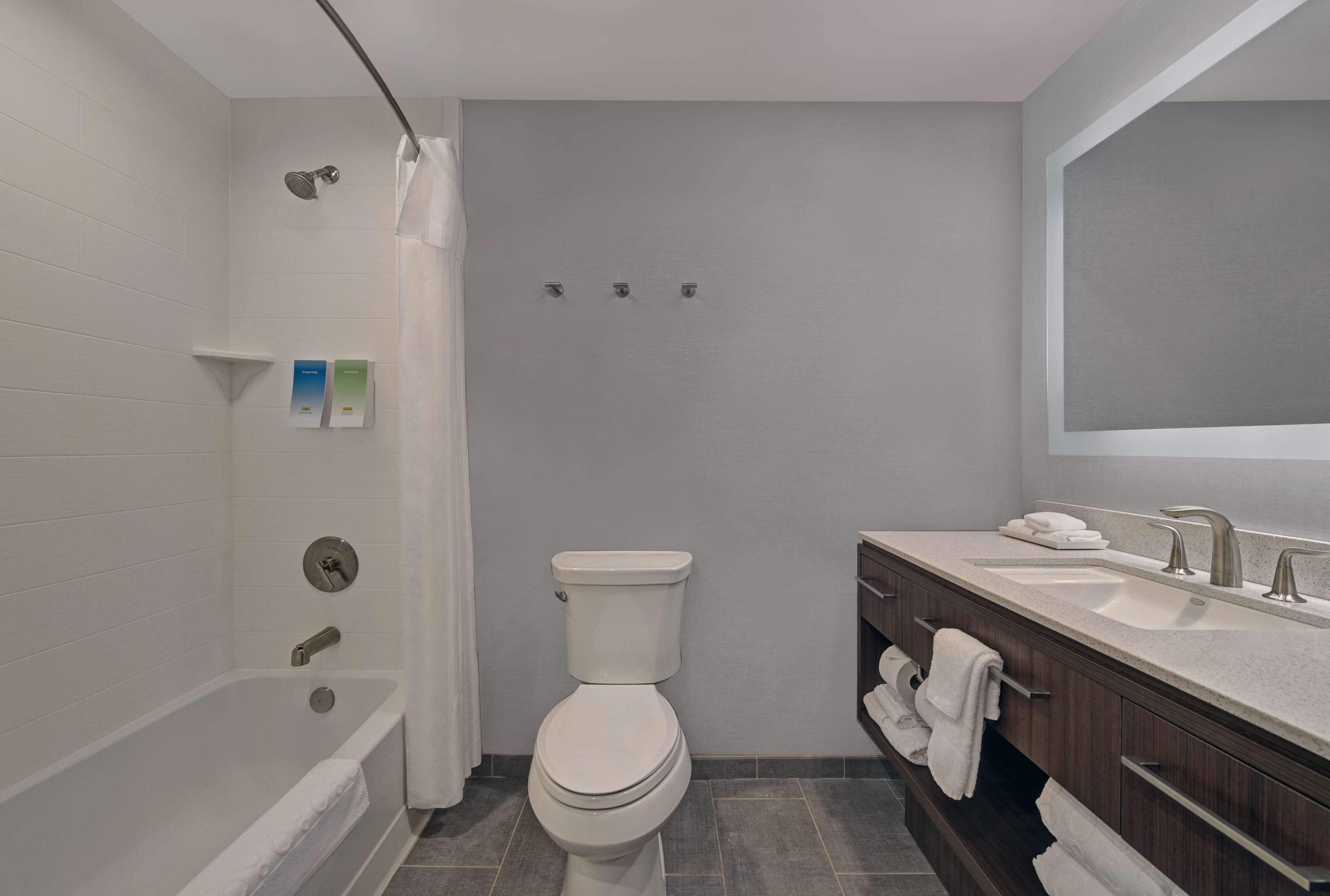 Et moderne badeværelse med badekar, toilet og vaskebord med spejl.