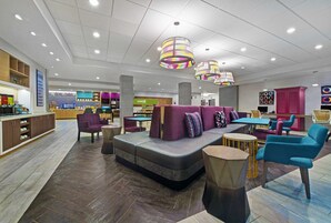 A modern lobby with a seating area, a reception desk, and a 'HOME' sign.