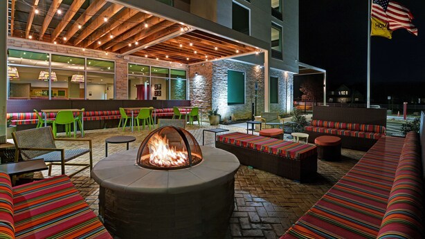 Un patio al aire libre con asientos, una chimenea y una sección cubierta con mesas y sillas.