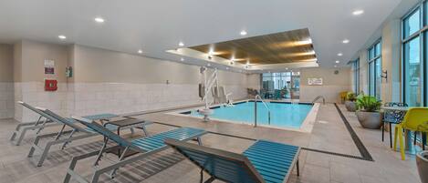 Un espace piscine comprenant des chaises longues, une piscine et une vue sur l’extérieur.