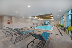 A pool area with lounge chairs, a pool, and a view of the outside.