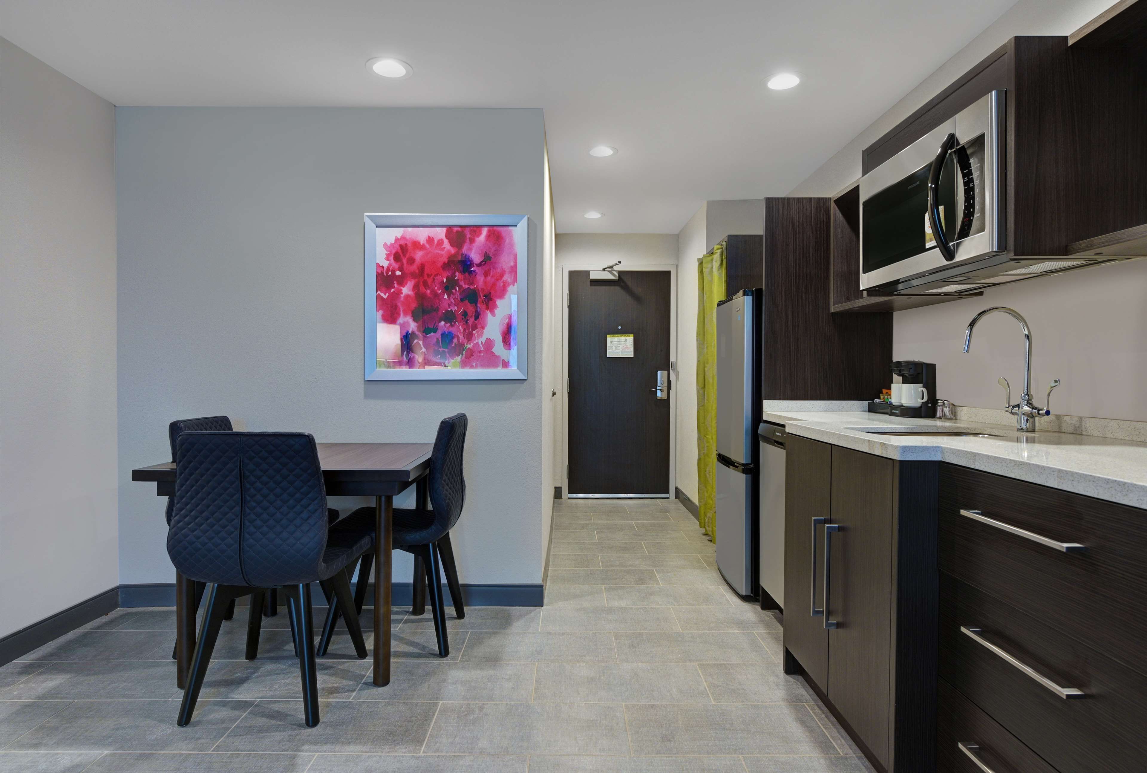 A modern kitchen with dark cabinetry, a stainless steel microwave, and a countertop with a sink.