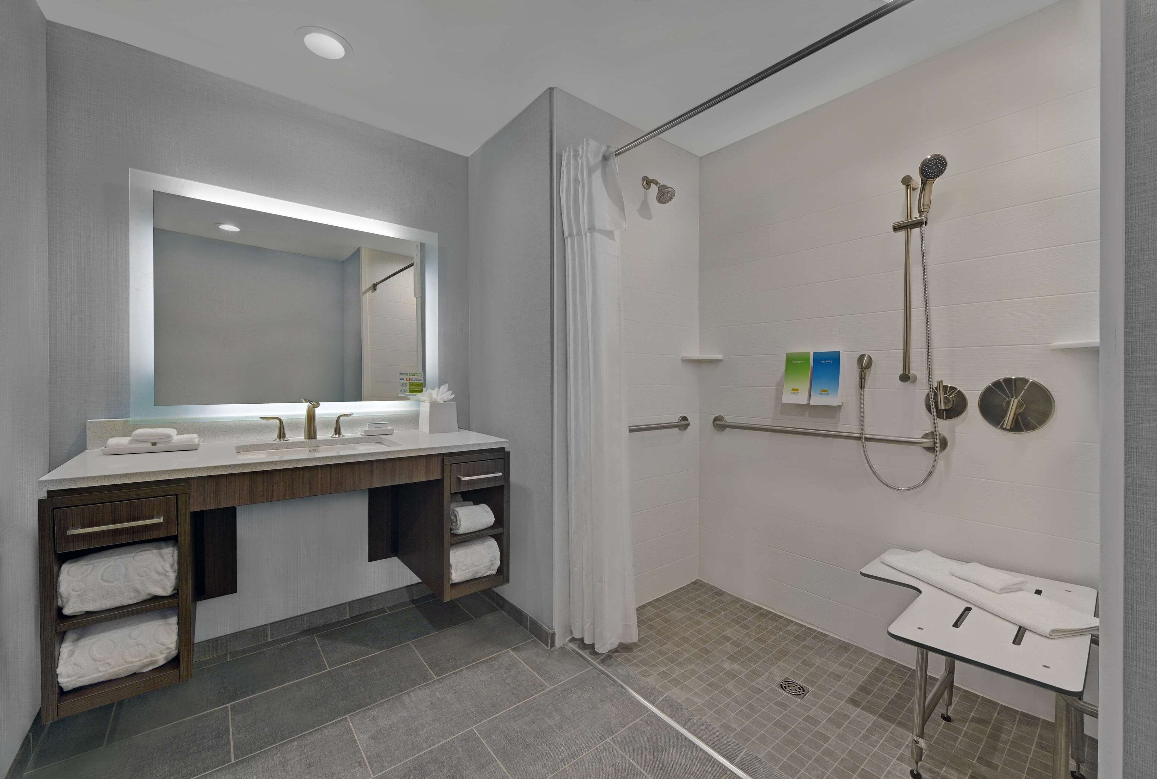 Un baño moderno con ducha, tocador con espejo y un perchero para toallas.