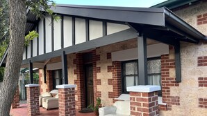 A house with a covered porch, brick walls, and a stone pathway.