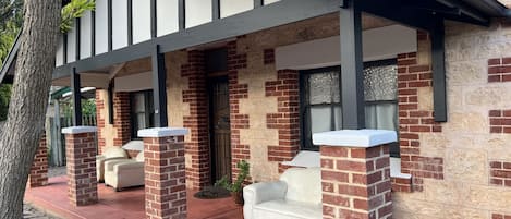 A house with a covered porch, brick walls, and a stone pathway.