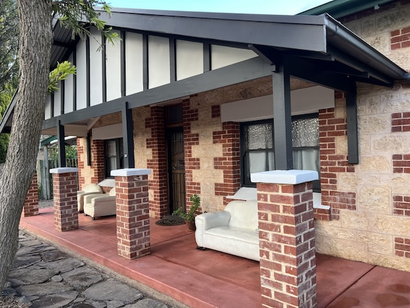 A house with a covered porch, brick walls, and a stone pathway.
