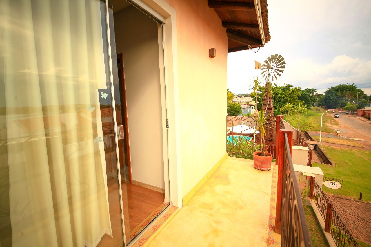 A balcony with a view of a windmill, a road, and greenery.