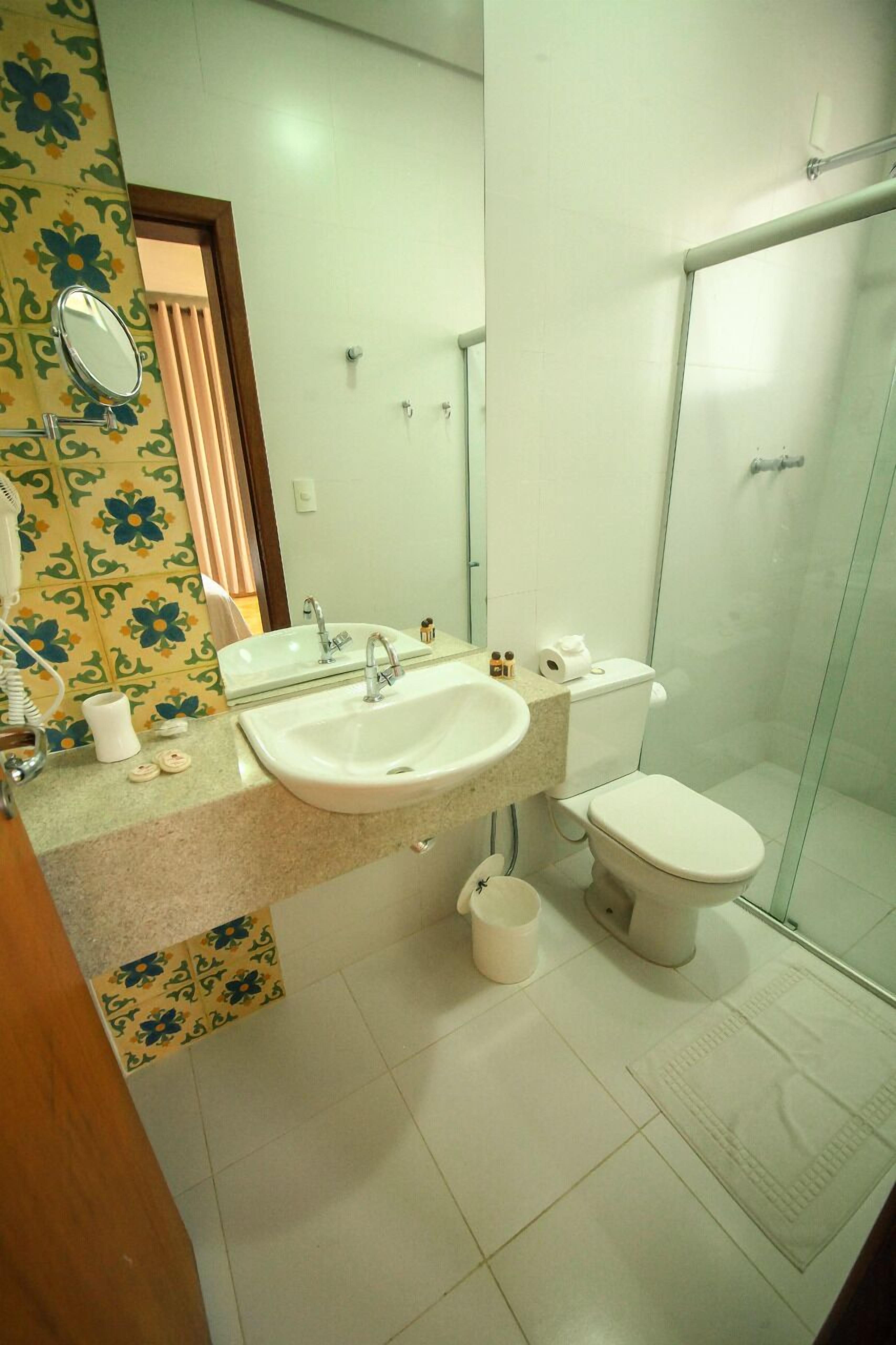 Un baño con lavamanos, inodoro y cabina de ducha de vidrio.