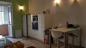 Ett kompakt kök med kylskåp, mikrovågsugn och en liten matplats med bord och stolar.
