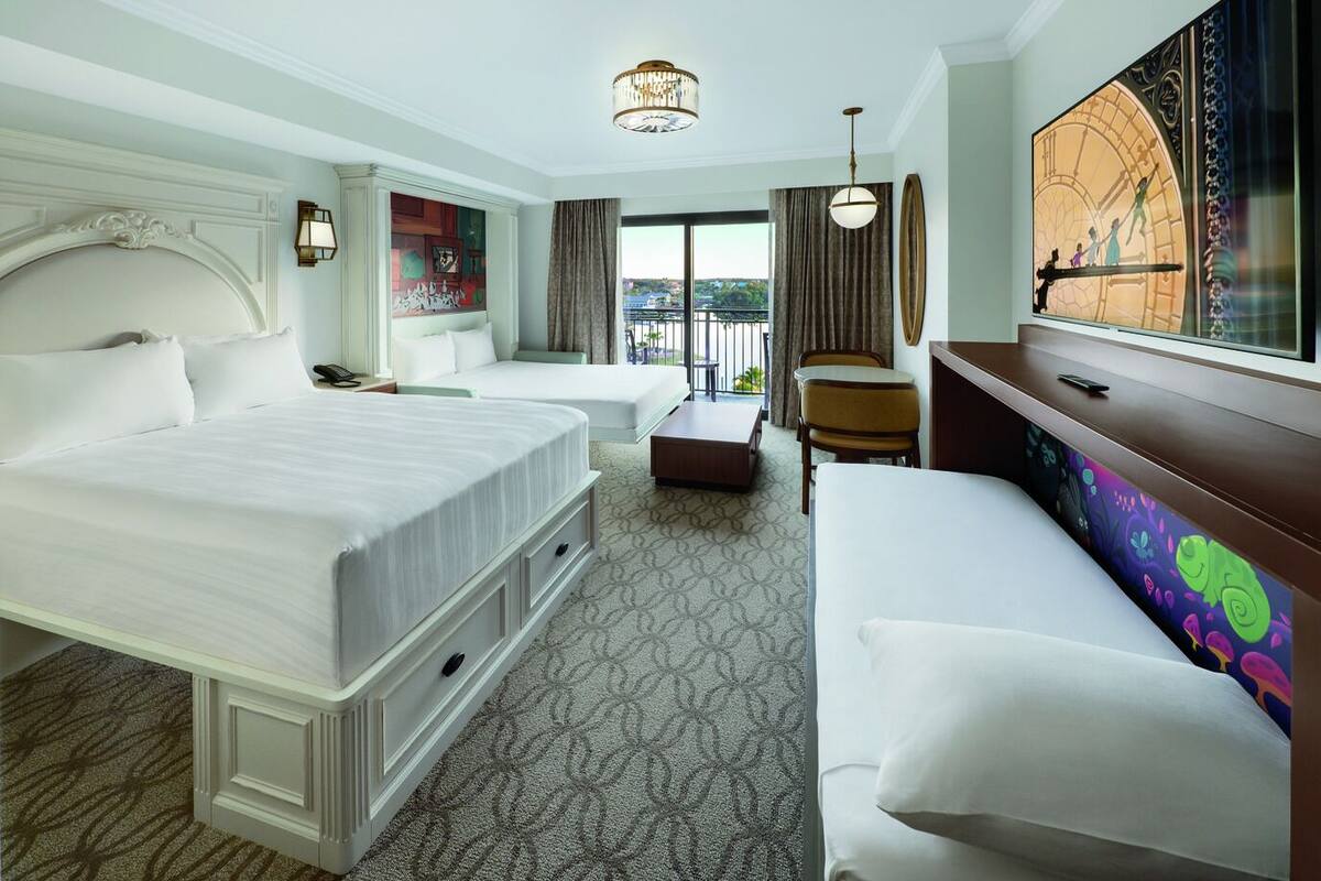 A hotel room with a large bed, a sofa, a desk, and a view of the outdoors.
