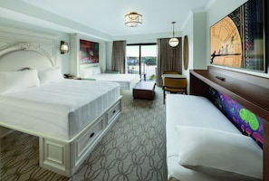 A hotel room with a large bed, a sofa, a desk, and a view of the outdoors.