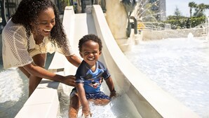 A person sliding down a water slide with a child.