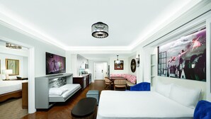 Una habitación de hotel moderna con una cama grande, un escritorio, un sofá y un comedor.