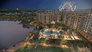 Un resort con una piscina grande, varias edificaciones y un espectáculo de fuegos artificiales al fondo.