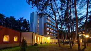 A multi-story hotel with a modern design, featuring balconies on each floor and a well-lit entrance. - Millennium Spa (Dziwnów)