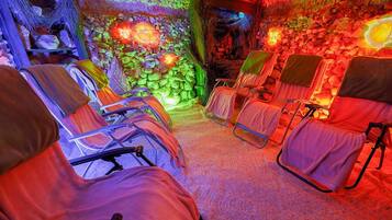 Relax in a serene space with a stone wall and lush greenery, surrounded by comfortable reclining chairs.