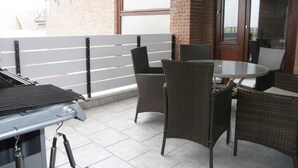 A patio with a grill, wicker chairs, and a glass table. - At the gates of Hamburg in the old country (Mittelnkirchen)