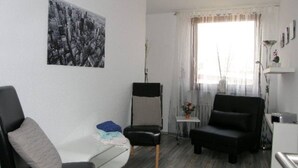 A modern living room with a sofa, a chair, a small table with a vase of flowers, and a painting on the wall. - At the gates of Hamburg in the old country (Mittelnkirchen)