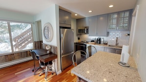 A modern kitchen with granite countertops, stainless steel appliances, and grey cabinetry.