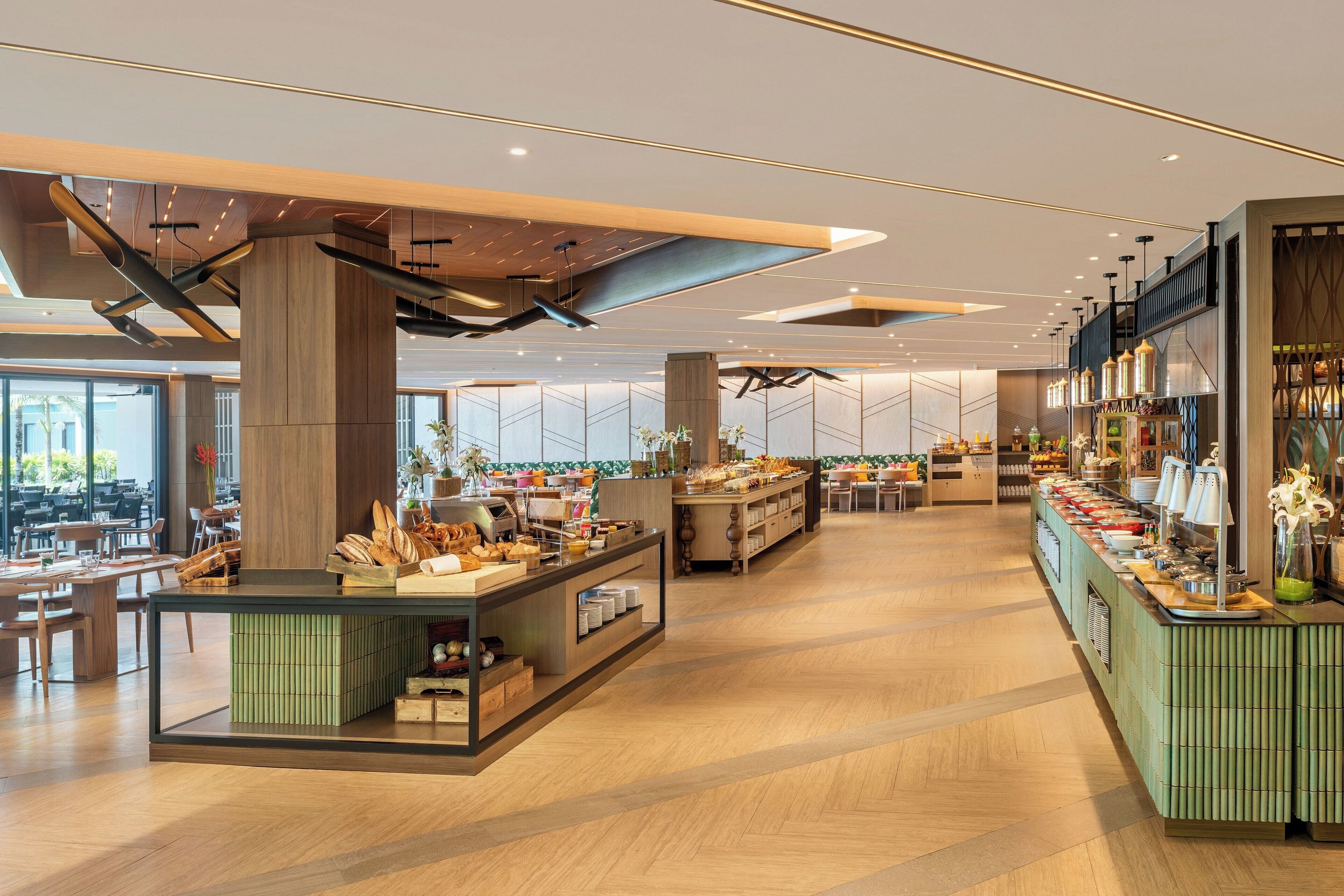 A modern hotel lobby with a central buffet area, seating arrangements, and a large window providing natural light.